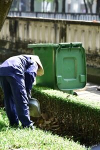 Worker handling same day garden waste removal Dubai with a green waste bin