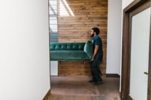 Same-day junk removal team in Dubai carrying a sofa out of an apartment