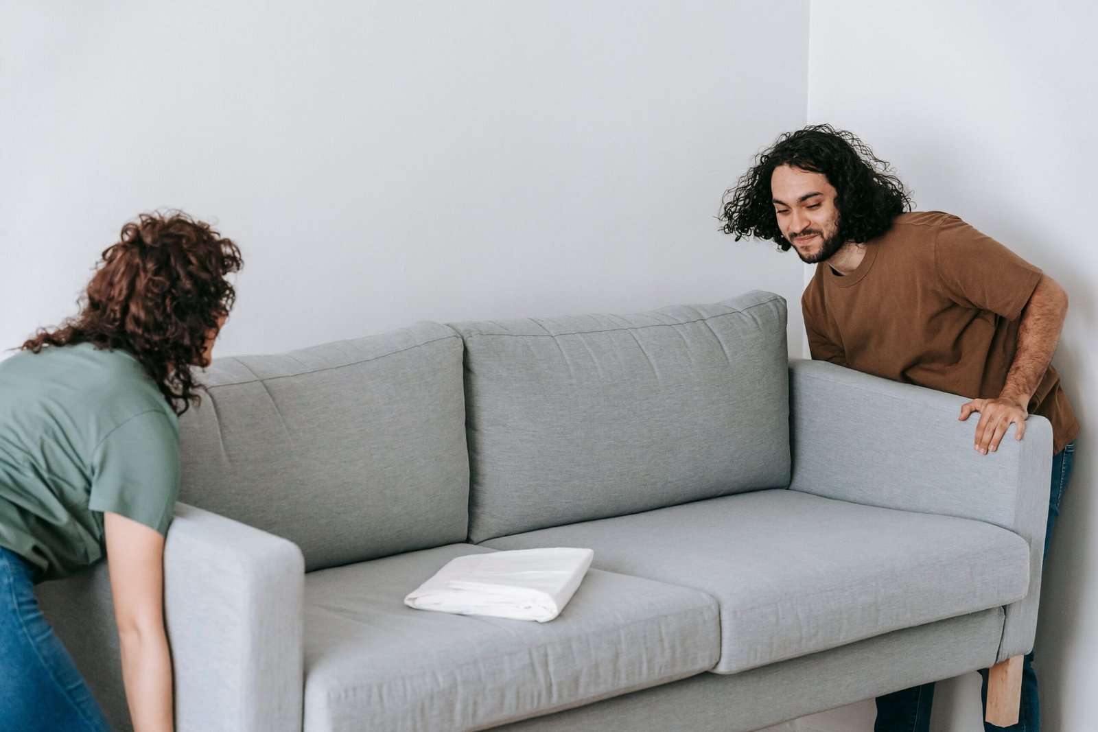 Couple lifting a sofa inside a Dubai apartment before professional sofa removal collection