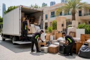 A rubbish removal crew loading old furniture and boxes into a van outside a Dubai residential building